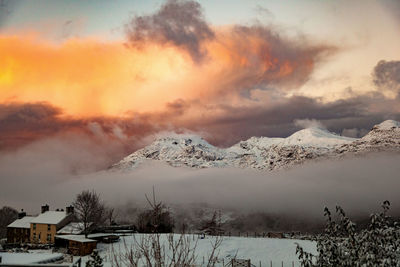 Scenic view of snow covered mountains against sky at sunset