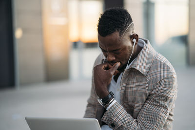 Man using laptop while listening to music