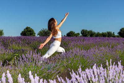 Woman in a lavender field doing the warrior yoga pose