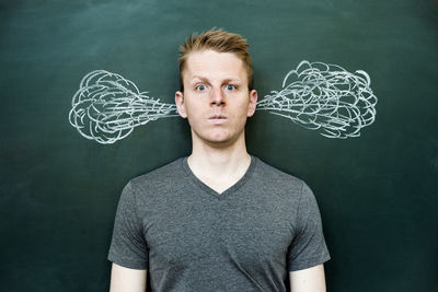 Portrait of young man standing against wall