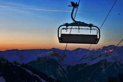 Overhead ski lift  against snowcapped mountains during sunset