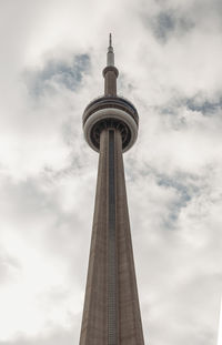 Looking up at the cn tower in toronto, canada against a cloudy sky.