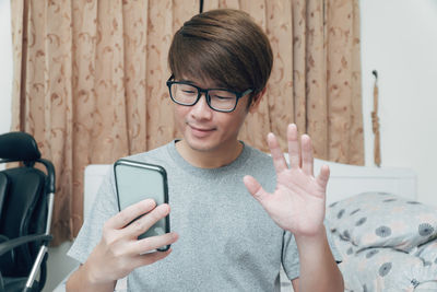 Portrait of smiling man using mobile phone on bed