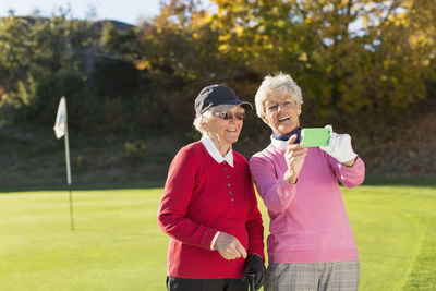 Senior female golfers photographing on golf course