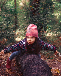 Portrait of young woman sitting on tree