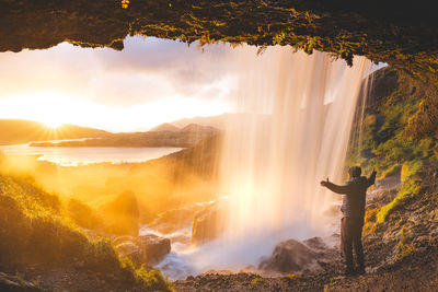 Scenic view of waterfall against sky during sunset