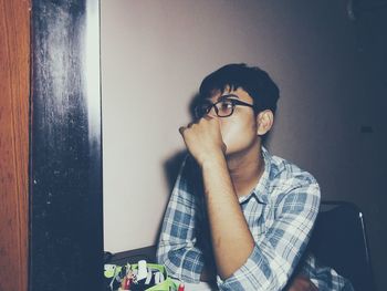 Thoughtful young man sitting on chair at home