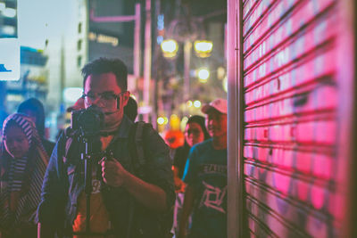 People standing by illuminated lights at night