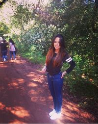 Portrait of smiling young woman standing against trees