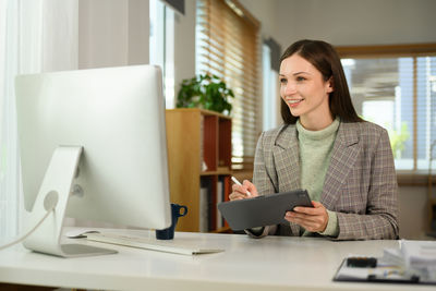 Portrait of young woman using laptop at office