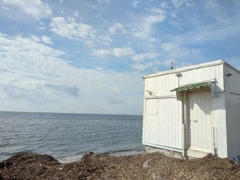 Built structure on beach by sea against sky