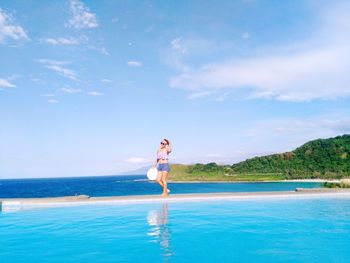 Full length of woman by infinity pool at beach