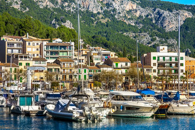 Sailboats moored on harbor by buildings in city