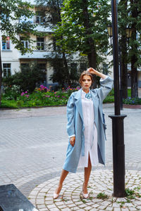 Fashionable young woman wearing blue overcoat at public park