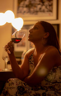 Side view of a young woman drinking glass