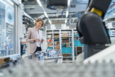 Businesswoman examining workpieces in a modern factory hall