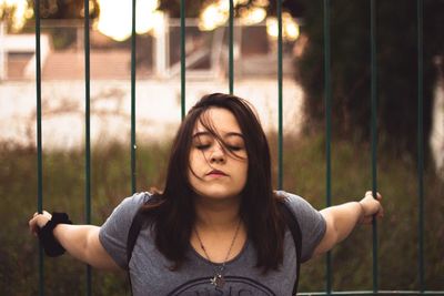 Close-up of young woman standing against gate