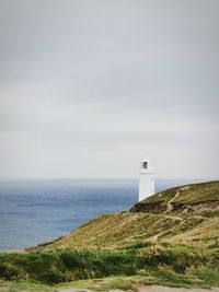 Lighthouse by sea against sky