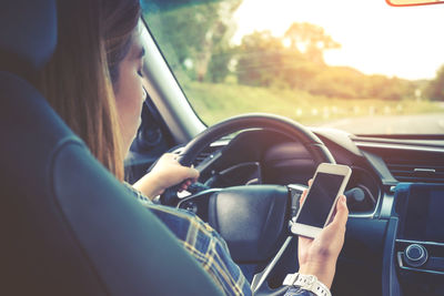 Woman using mobile phone while driving car