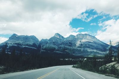 Road by mountains against sky