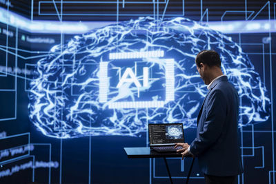 Digital composite image of businessman using laptop