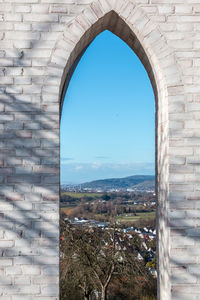 Buildings against clear blue sky seen through window
