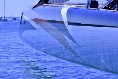 Close-up of sailboats moored on sea against blue sky