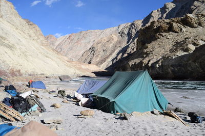 Tents at campsite on zanskar riverbank amidst rocky mountains