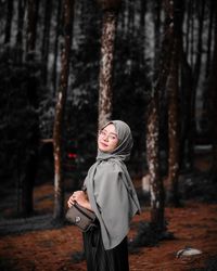 Portrait of young woman standing in forest