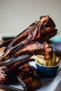 Close-up of roasted ribs in serving tongs