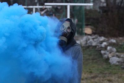 Man wearing gas mask while standing by distress flare