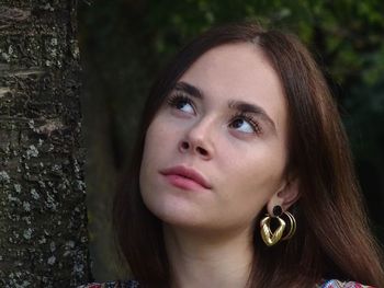 Close-up portrait of young woman with tree trunk