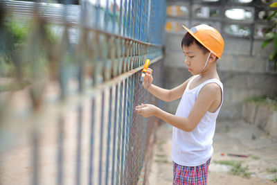 Side view of boy looking through fence