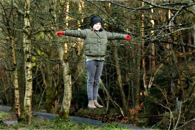 Cute girl levitating against trees in forest