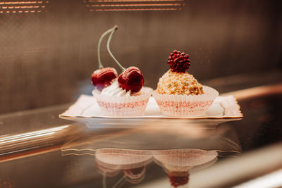 Sweet tiny cakes with fluffy cream and red cherries. delicious dessert