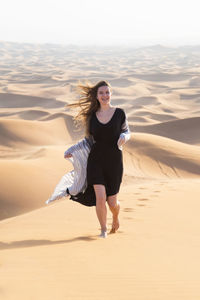 Full length of young woman on sand dune