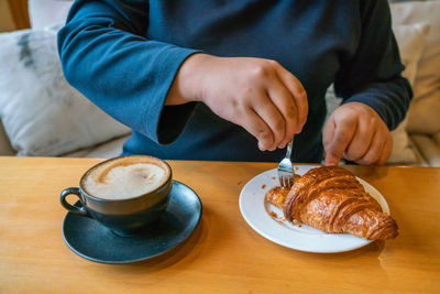 Midsection of man with coffee cup on table