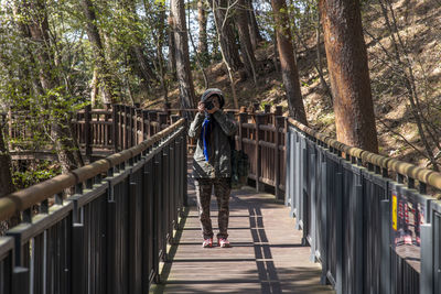 Woan taking a photo on footbridge