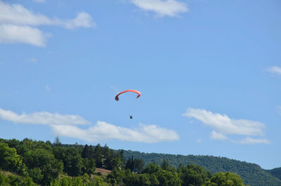 Low angle view of person paragliding against sky