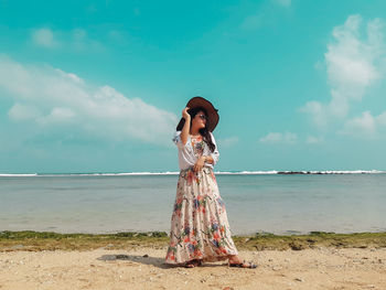 Woman standing at beach against sky