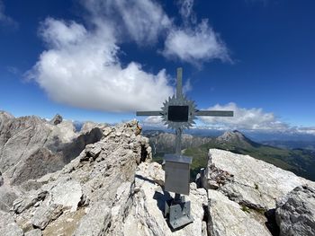 Panoramic view of cross on rock against sky