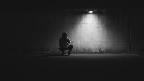 Full length of a man sitting on wall at night