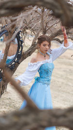 Woman in dress standing against bare trees