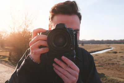 Close-up of man photographing against sky