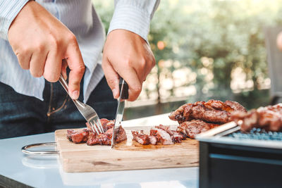 Midsection of man preparing food on barbecue grill