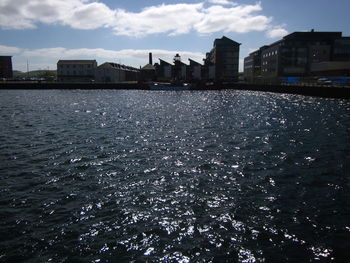 Sea by buildings against sky in city