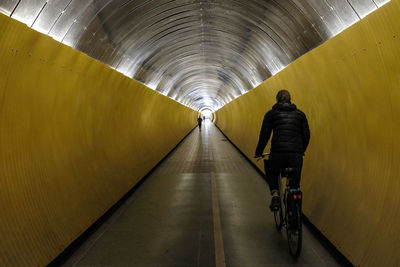 Rear view of man in illuminated tunnel