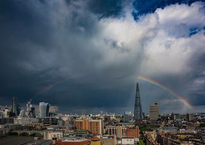 View of rainbow over city against cloudy sky