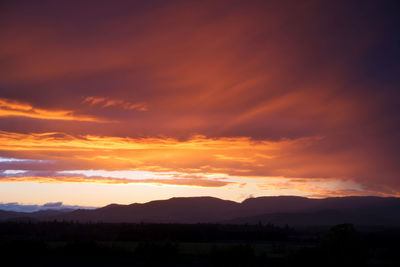 Scenic view of silhouette mountains against orange sky