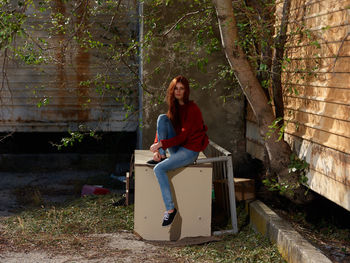 Full length of woman sitting on plant against trees